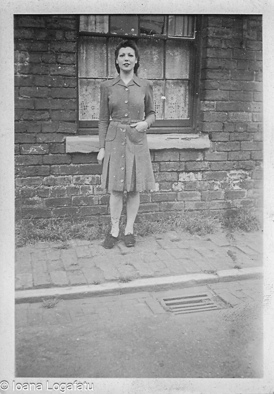 Woman in vintage dress stands by old brick wall
