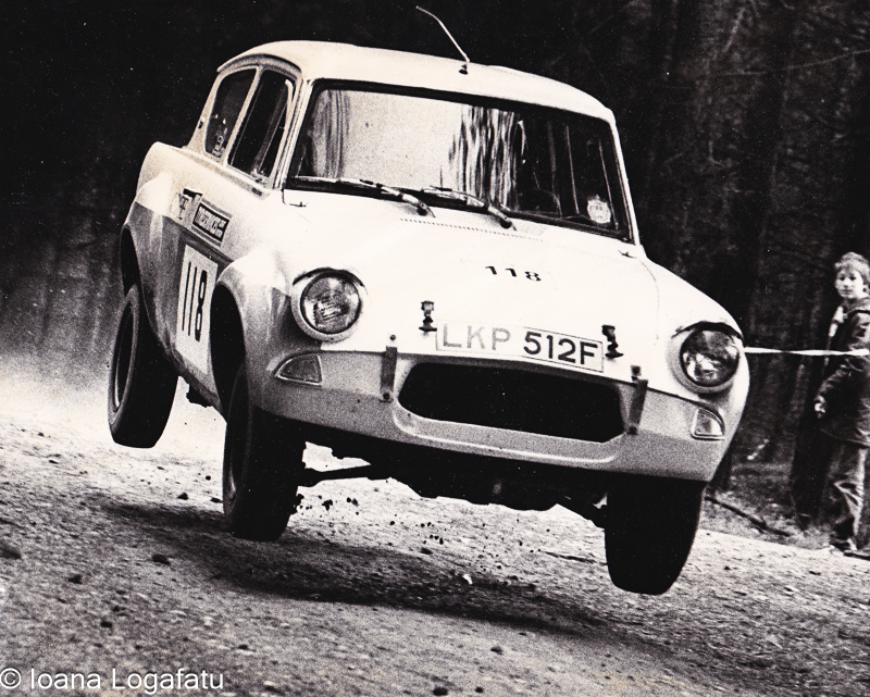Classic rally car leaps over dusty terrain