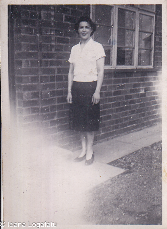 Woman standing beside brick building in early era