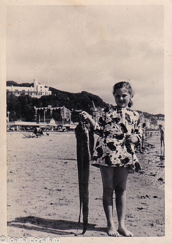 Young girl proudly holds a long fish at the beach