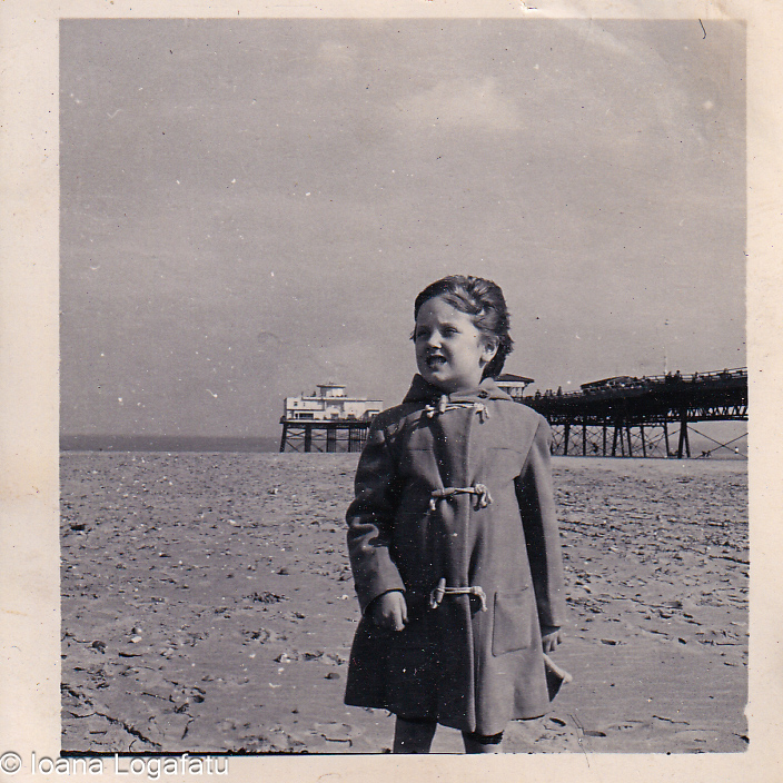 Child in a raincoat enjoying a sandy beach day
