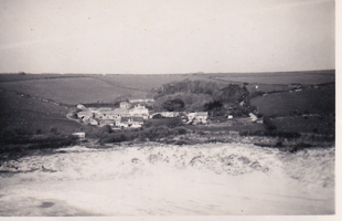 Coastal village among green hills and waves