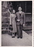 Couple stands together in vintage attire outdoors