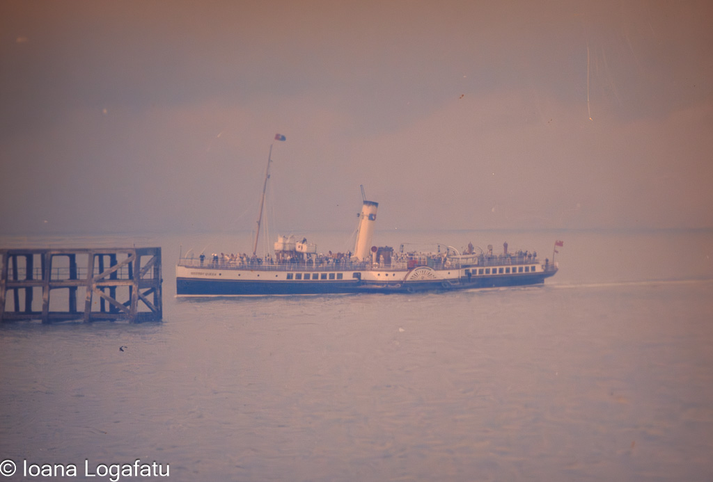 Boat sailing near pier in calm waters at sunset