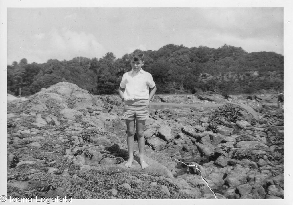 Young boy exploring rocky shore during summer