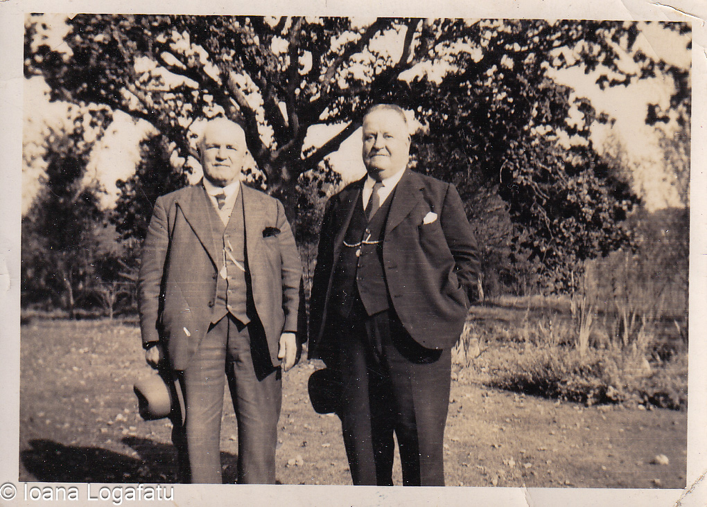 Two gentlemen stand proudly in a tranquil garden