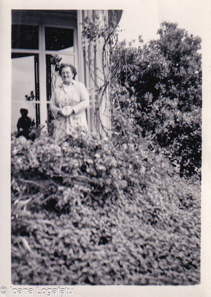 Woman standing amid lush greenery near a window