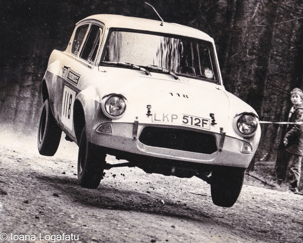 Classic rally car leaps over dusty terrain