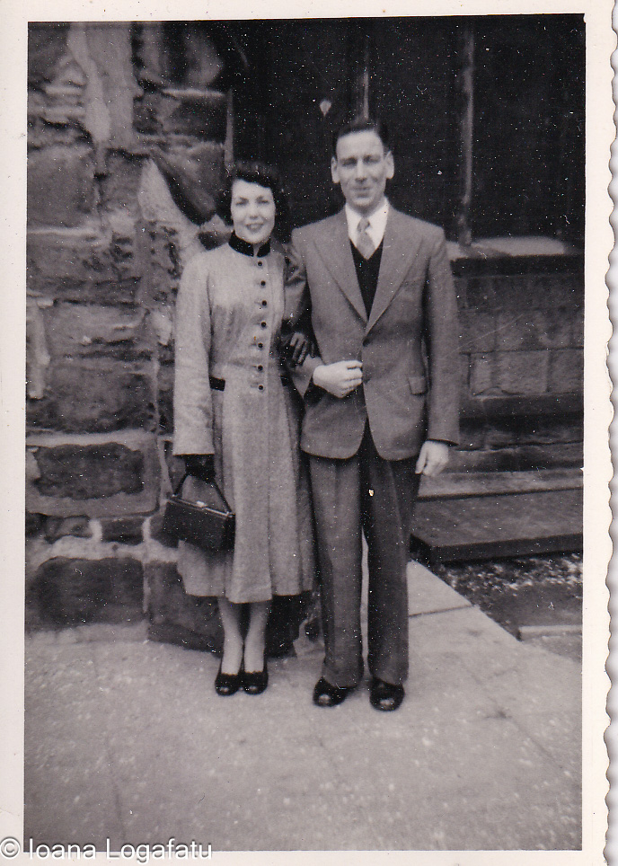 Couple stands together in vintage attire outdoors