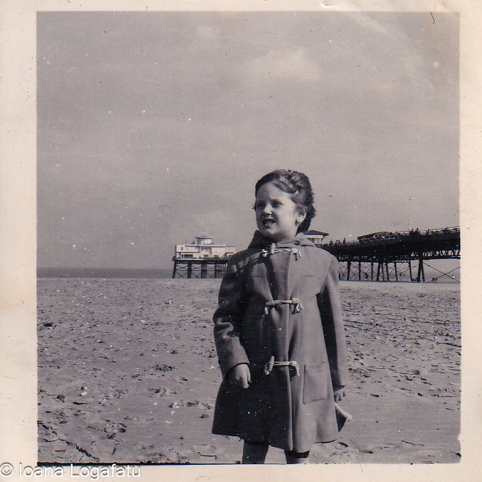 Child in a raincoat enjoying a sandy beach day