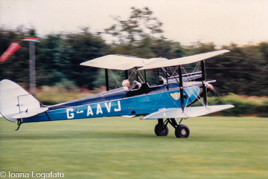 Vintage biplane gracefully landing on green field