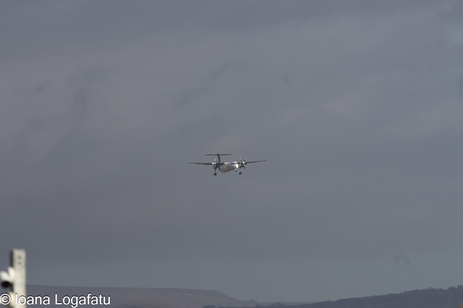 Airplane gliding through a cloudy sky at sunset