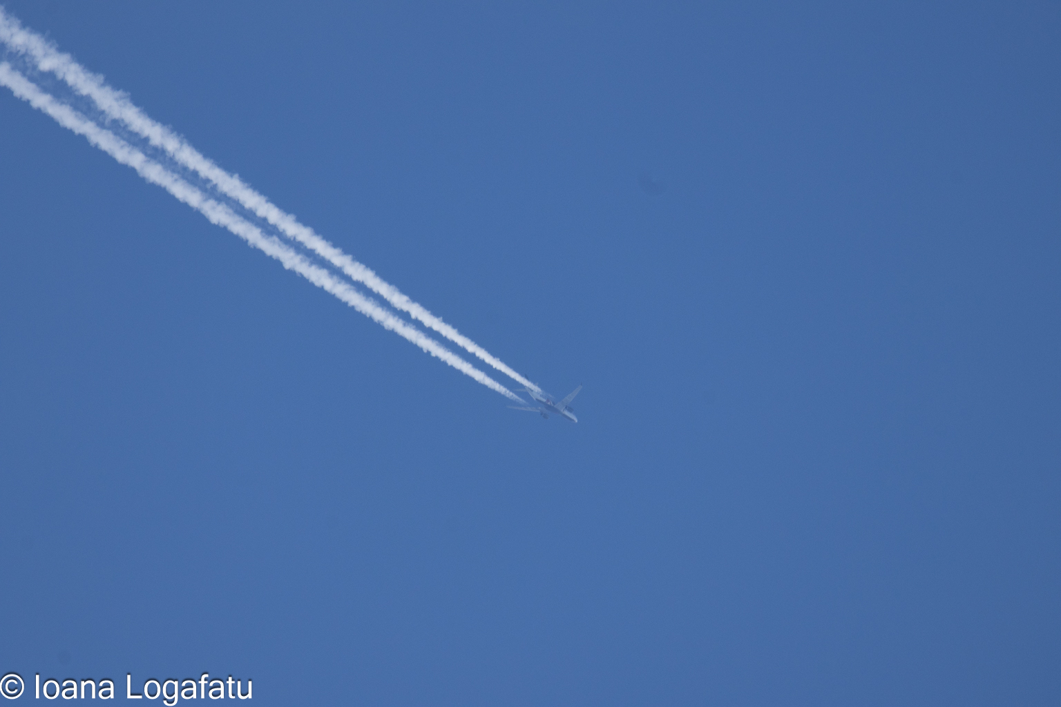 High above, a plane leaves trails in the sky