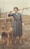 Woman in a blue dress playing with a dog outside