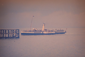 Boat sailing near pier in calm waters at sunset