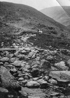 Mountain trail with rocky stream and rider