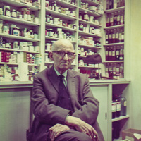 Elderly man sitting in a vintage pharmacy setting