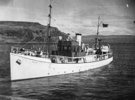 Historic vessel sailing in calm waters near cliffs
