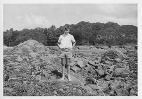 Young boy exploring rocky shore during summer