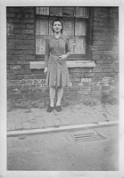 Woman in vintage dress stands by old brick wall