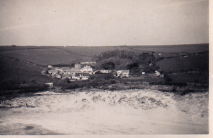 Coastal village among green hills and waves