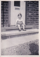 Child on porch steps, black and white