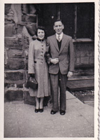 Couple stands together in vintage attire outdoors