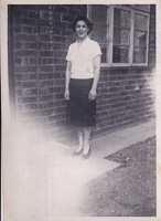 Woman standing beside brick building in early era