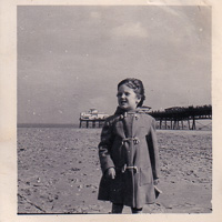 Child in a raincoat enjoying a sandy beach day