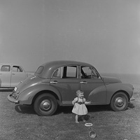 Child plays joyfully by classic cars