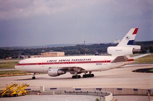 Historic aircraft in flight at a bustling airport