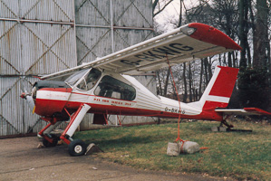 Vintage aircraft resting beside an old hangar
