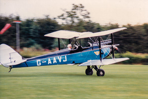 Vintage biplane gracefully landing on green field